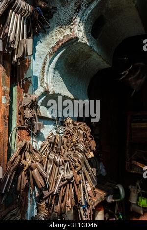 Large bunches of old iron keys hang from wire loops on a weathered turquoise wall in a traditional locksmith workshop in Jodhpur. Stock Photo