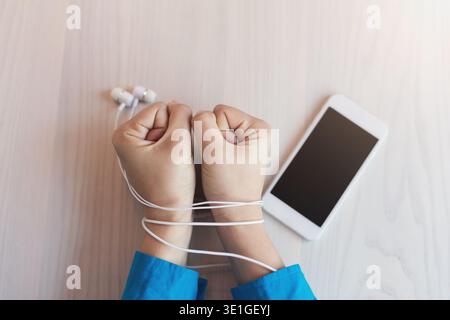 Hands of woman bound with earphones wire on white table Stock Photo