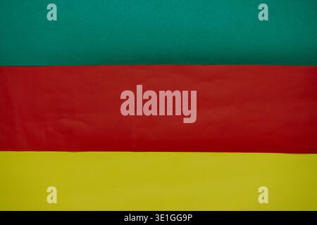 A striking abstract background featuring three distinct horizontal stripes of green, red, and yellow paper, creating a vibrant and colorful design per Stock Photo