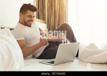 Businessman sitting on bed and using laptop Stock Photo