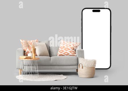 Comfortable sofa and mobile phone with blank screen on grey background Stock Photo