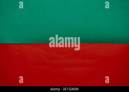 A vibrant and colorful abstract background featuring a clear horizontal split between bright green and bold red textured paper. Stock Photo