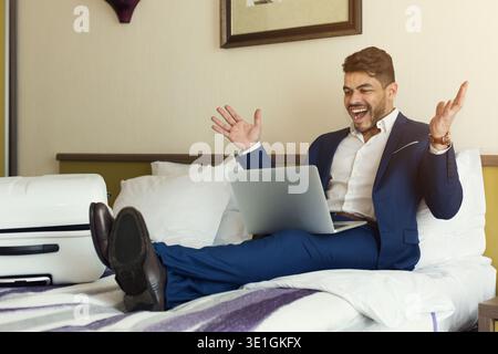 Businessman sitting on bed and using laptop Stock Photo