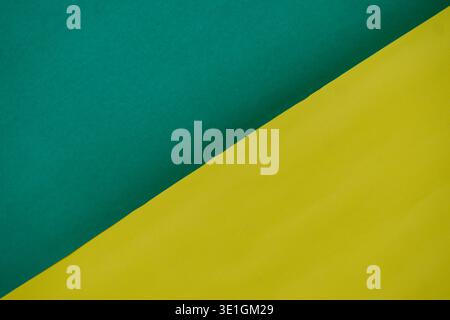 A striking abstract background showcasing a diagonal split between vibrant green and yellow colored paper with subtle texture, perfect for modern desi Stock Photo