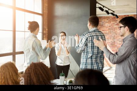 Young team clapping hands to colleague at meeting Stock Photo