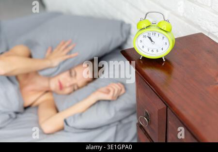 Young woman covering ears with pillow in bed Stock Photo