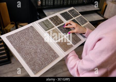 woman choosing carpet tile design from samples book in flooring shop Stock Photo