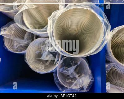 close up view of multiple corrugated metal tubes, each individually protected by clear plastic sheeting, stored within a blue industrial container Stock Photo