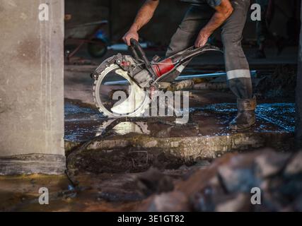 A worker saws a concrete floor with a ring concrete cutter. Special device for sawing concrete. High quality photo Stock Photo