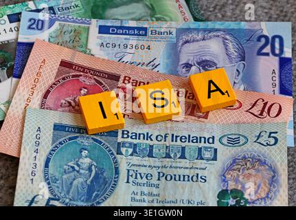 Scrabble letters spelling ISA on Northern Ireland sterling banknotes, illustrating the UK tax-free Individual Savings Account deadline at tax year end Stock Photo