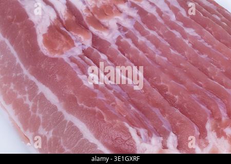 Studiolit raw bacon slices detailed. Closeup image of raw pink bacon with fat streaks. Detailed studio shot of raw pink bacon highlighting fat and mus Stock Photo