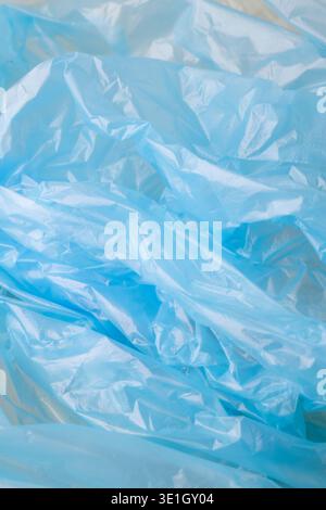 Crumpled blue plastic creating an abstract background texture. Showing wrinkles, folds, and highlights on transparent polyethylene material Stock Photo