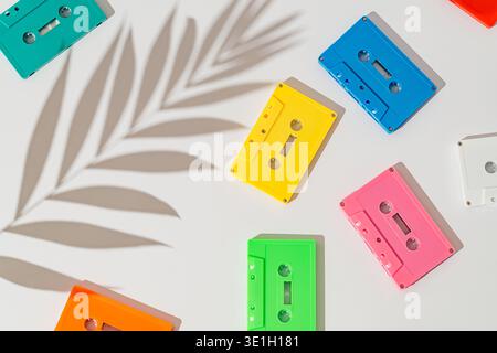 Colorful retro audio cassette tapes flat lay with palm leaf shadow on white background. 80s 90s nostalgia music background. Stock Photo