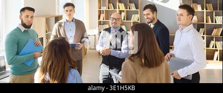 Teacher leading adult students in group meeting discussion in bright classroom Stock Photo