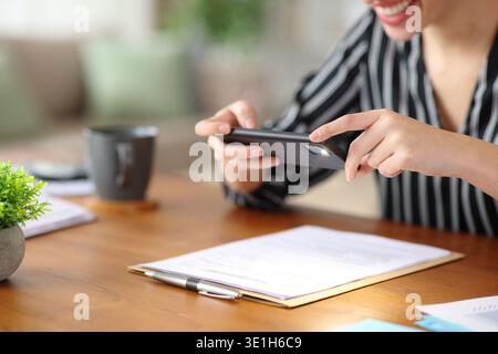 Close up of a happy self employed hands taking photo of paper document working at home Stock Photo
