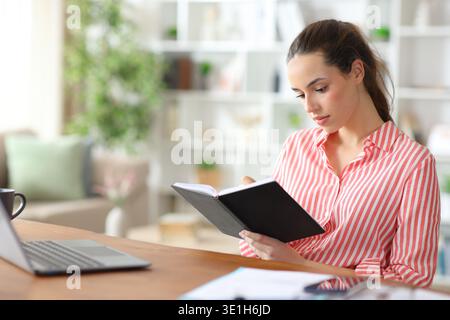 Serious freelance worker taking notes in agenda working at home Stock Photo