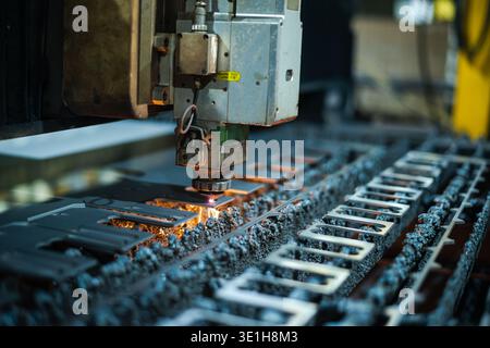 Laser cutting process with digital software control. The laser cutter head cuts through a sheet of metal, sending sparks. High quality photo Stock Photo