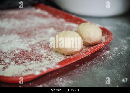 pieces of dough on a red tray covered with flour. The working environment in the bread workshop. High quality photo Stock Photo
