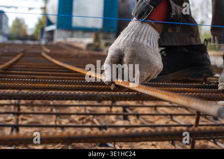 A worker's hand lays the bars of reinforcement in the future monolithic concrete. High quality photo Stock Photo