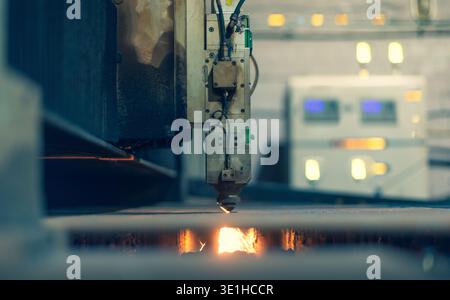 A laser machine with software cuts metal against the background of an electronic control center. A lot of glowing buttons and indicators on the laser Stock Photo