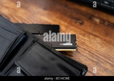Black DDR5 RAM memory modules placed inside a black wallet on wooden surface. RAM shortages on the market, rising prices, and increased demand driven Stock Photo