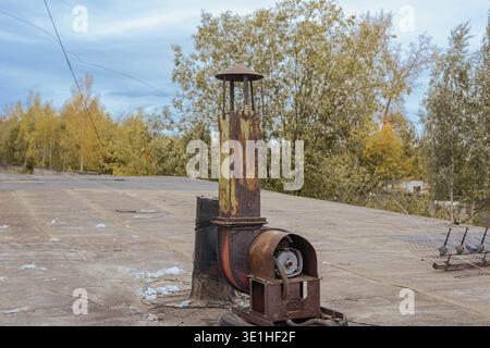 An old rusty exhaust system with a pipe and an electric motor is installed on the roof. High quality photo Stock Photo