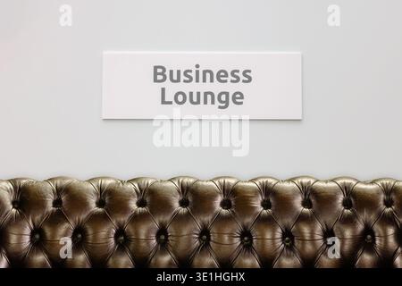 Business lounge sign on a white wall with chesterfield sofa in front Stock Photo