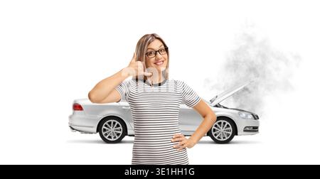Young woman gesturing a phone call in front of a broken car isolated on white background Stock Photo