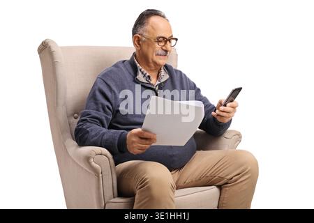 Mature man in an armchair with a phone and a paper document isolated on white background Stock Photo