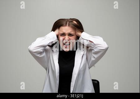 Young woman screaming in frustration, clutching head, feeling stress, anxiety, emotional pain and headache Stock Photo