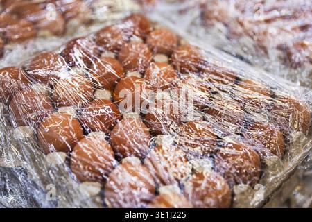 Close-up of Brown Chicken Eggs in Cardboard Tray Wrapped in Plastic Film Stock Photo