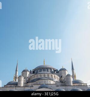 Majestic Ottoman-style mosque featuring large central dome, smaller surrounding domes, and tall minarets with golden crescents. Built from light stone Stock Photo