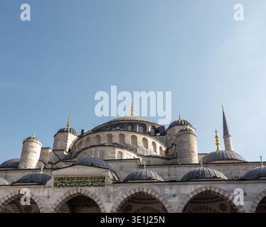 Historic Ottoman-style mosque featuring large central dome, smaller surrounding domes, tall minarets, and ornate stone architecture with Islamic calli Stock Photo
