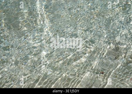 Clear shallow seawater flowing over sandy seabed with sunlight creating ripple patterns on ocean floor Stock Photo