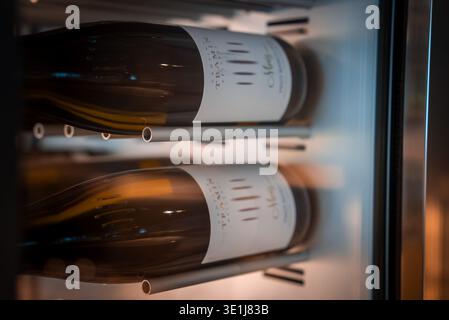 Wine bottles on metal rails in fridge, San Domenico, Italian Alps Stock Photo