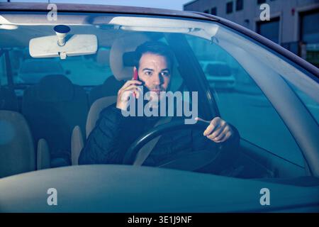 Driver distracted using mobile phone while driving car Stock Photo