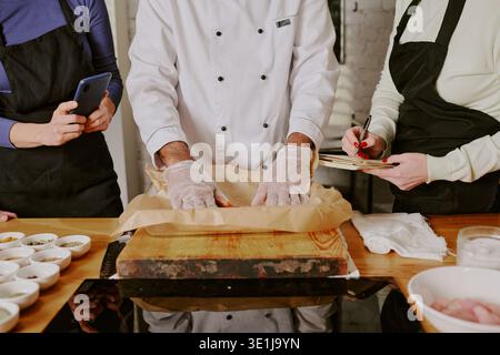 Middle Aged Man Teaching Cooking Class with Students Observing Stock Photo