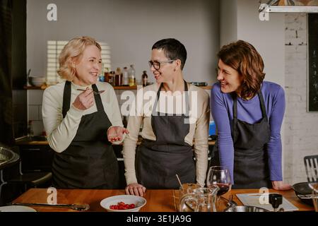 Three Middle Aged Caucasian Women Smiling and Interacting during Cooking Class Stock Photo