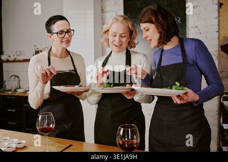 Three Caucasian Middle Aged Women Tasting Food during Cooking Class Stock Photo