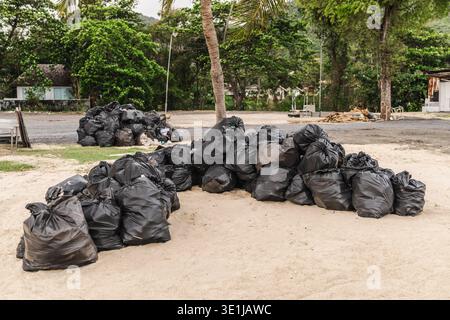 Pile of garbage bags collected on tropical beach after festival cleanup Koh Samui Thailand Stock Photo