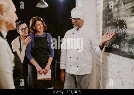 Middle Aged Chef Teaching Cooking Class to Diverse Young Adults Stock Photo