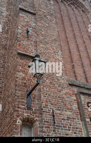 Leeuwarden, friesland, netherlands, Cast iron street lamp fixed to an old brick church wall featuring architectural details Stock Photo