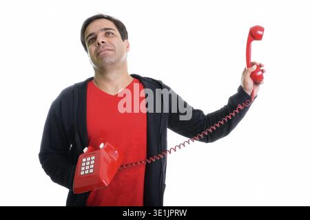 Studio shot of thoughtful young Persian man holding old telephone away while looking annoyed isolated against white background Stock Photo