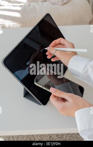 Woman Using Stylus on Tablet and Checking Phone – Digital Creativity, Modern Technology Stock Photo