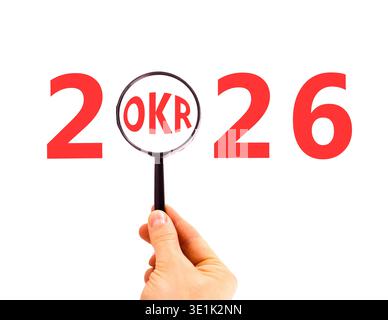 2026 OKR objectives and key results symbol. Concept words 2026 OKR in magnifying glass. Beautiful white background. Businessman's hand. Business 2026 Stock Photo