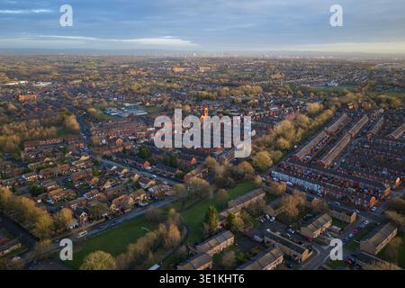 Aerial image looking southeast from Bolton toward the distant skyscrapers of Manchester and Salford, framed by lush suburban greenery. Stock Photo