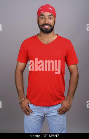 Studio shot of young handsome Indian man against gray background Stock Photo
