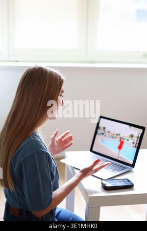 Young woman watching travel content on laptop while planning vacation. Digital lifestyle and tourism concept. Stock Photo