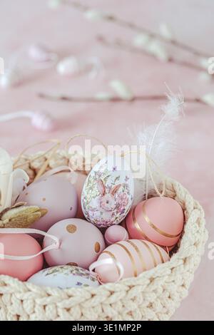 Easter decoration with pink and purple eggs with a bunny motif in a woven basket, pink background Stock Photo