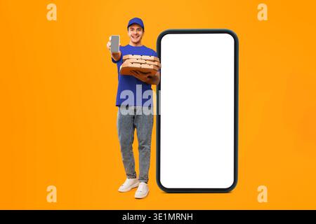 Young Man Delivers Pizza While Holding a Phone in Front of a Blank Smartphone Screen Stock Photo